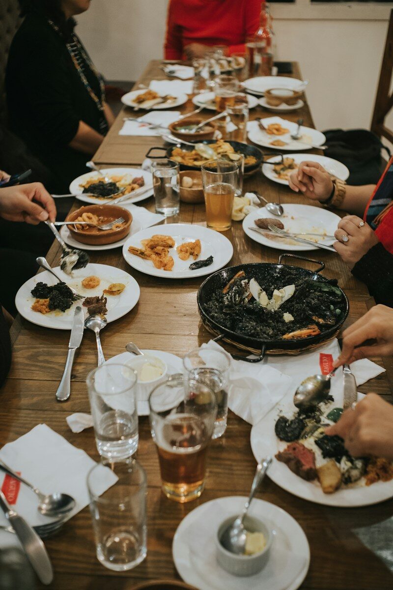 Grupo de personas sentadas en torno a una mesa compartiendo comida